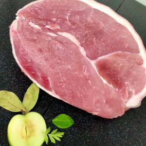 Fresh gammon joint garnished with half an apple and various fresh herbs