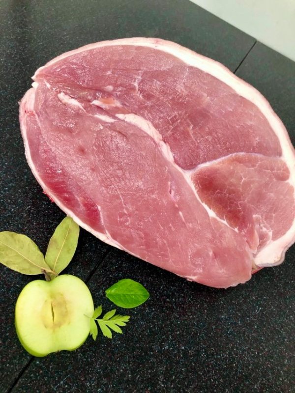 Fresh gammon joint garnished with half an apple and various fresh herbs