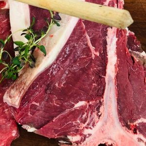 Fresh T-bone steak garnished with a sprig of thyme