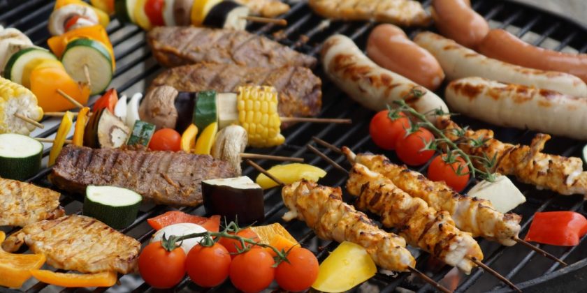 Selection of meats and vegetables cooking on barbecue grill